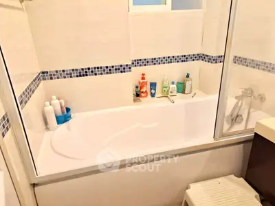 Cozy bathroom with bathtub and modern tiled design, ideal for relaxation.