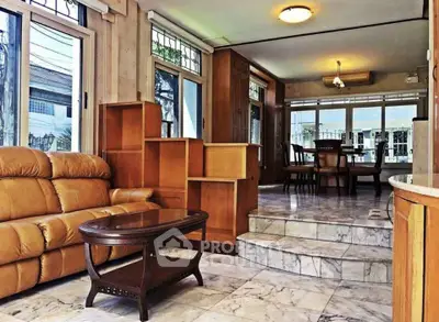 Spacious living room with marble flooring and elegant wooden furniture in a bright, airy home.