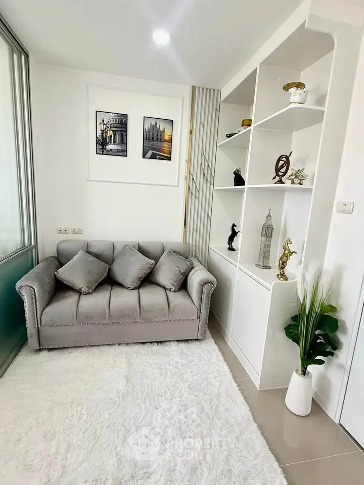 Chic living room with plush gray sofa, elegant decor, and modern shelving in a bright, inviting space.