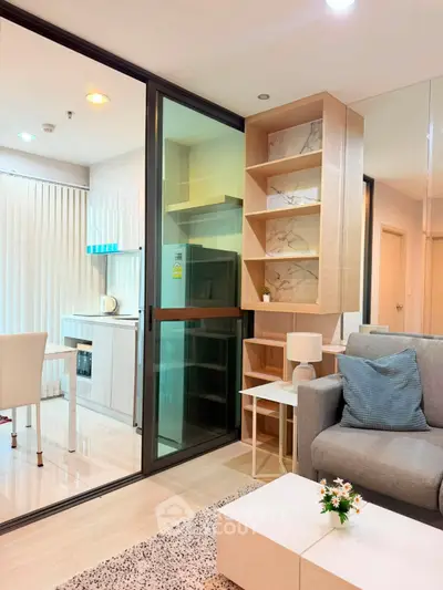 Modern living room with open kitchen, stylish shelving, and cozy seating area in a contemporary apartment.
