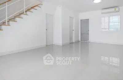 Spacious minimalist interior with sleek staircase and bright natural lighting.