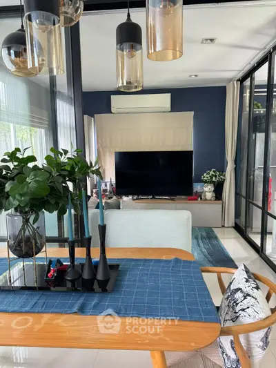 Modern living room with stylish decor and large TV, featuring elegant lighting and a cozy atmosphere.