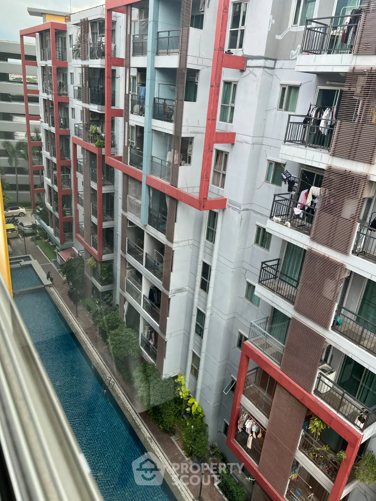 Modern apartment building with pool view and colorful balconies, ideal for urban living.