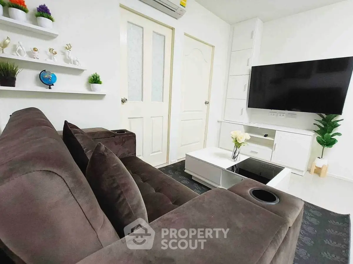Modern living room with plush sofa, wall-mounted TV, and stylish decor in a cozy apartment.