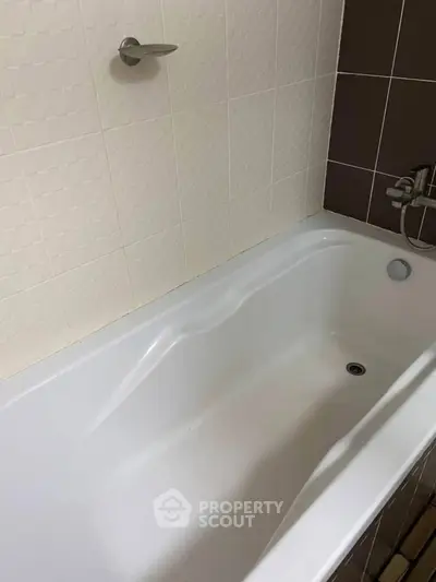 Modern bathroom with sleek white bathtub and stylish tile design.