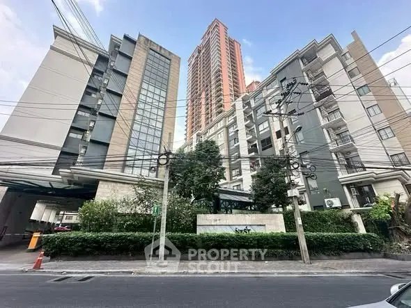 Modern high-rise residential building with lush greenery and urban surroundings.