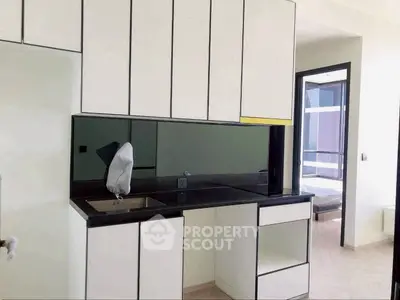 Modern kitchen with sleek cabinetry and black countertops in a contemporary apartment.