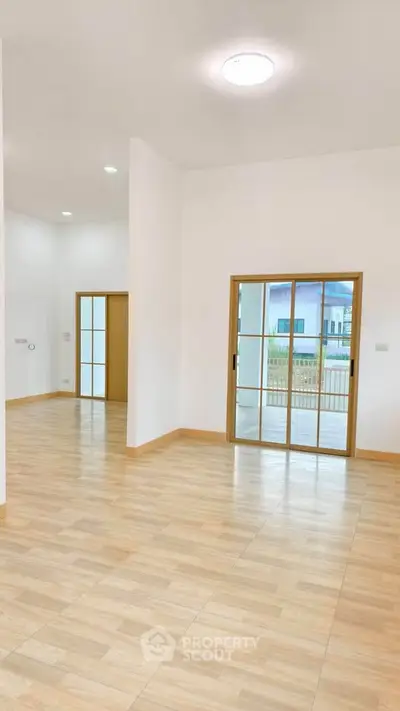 Spacious open-plan living area with sliding glass doors and wooden flooring