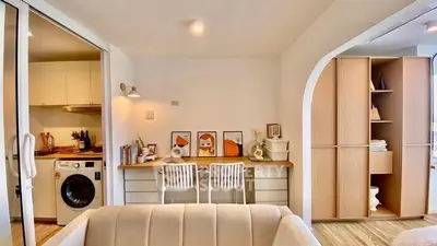Modern living room with study area and washing machine in open layout apartment.