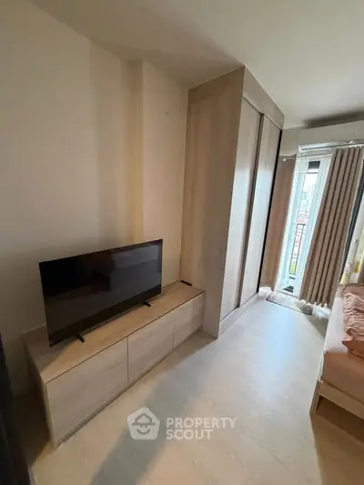Modern bedroom with sleek TV stand and large window for natural light