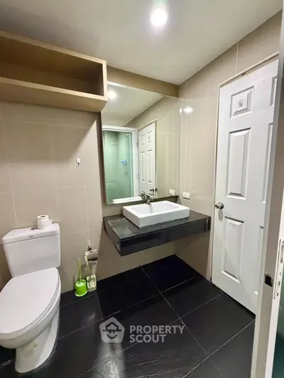 Modern bathroom with sleek fixtures and large mirror in a contemporary home.