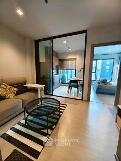 Modern open-plan living room with stylish kitchen and cozy bedroom view.