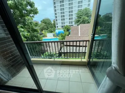 Spacious balcony with scenic view of lush greenery and modern building, perfect for relaxation.