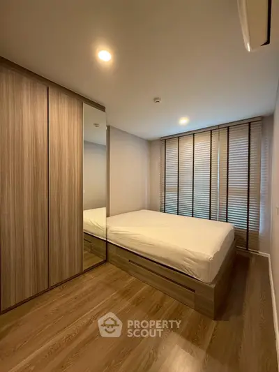 Modern bedroom with wooden flooring and built-in wardrobe in a cozy apartment.