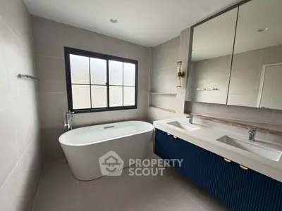 Modern bathroom with freestanding bathtub and dual sink vanity in elegant design.
