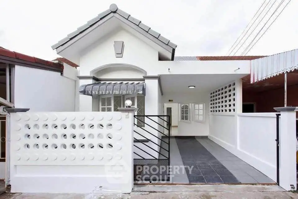 Charming white single-story house with modern facade and gated driveway.