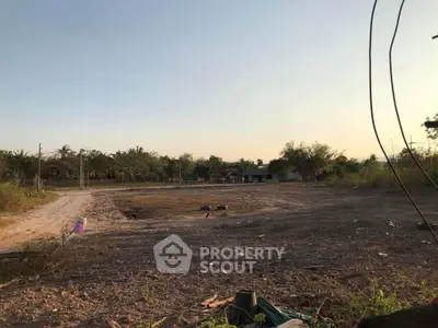 Expansive vacant land with potential for development, surrounded by lush greenery and clear skies.