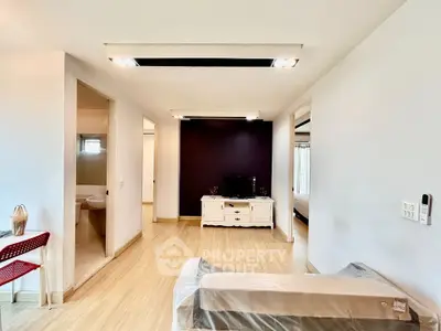 Spacious modern living room with sleek wooden flooring and stylish lighting, perfect for comfortable living.