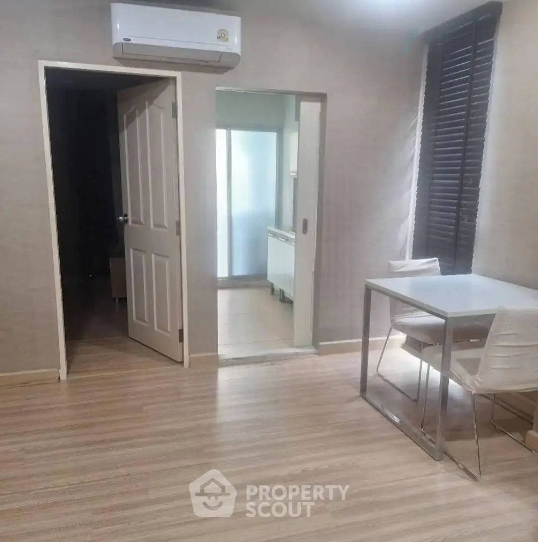 Modern apartment interior with sleek dining area and air conditioning, featuring wooden flooring and natural light.