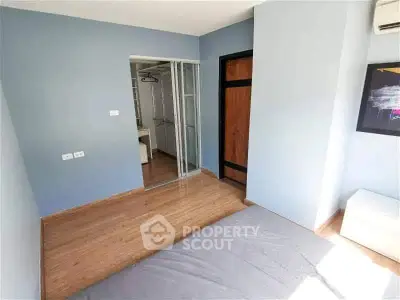 Spacious bedroom with wooden flooring and ample natural light