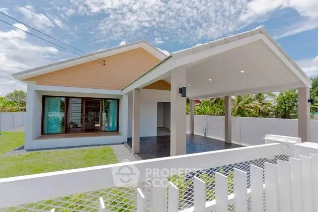 Charming modern house with spacious lawn and covered carport under a clear blue sky.