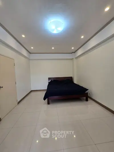 Spacious bedroom with modern lighting and sleek tiled flooring