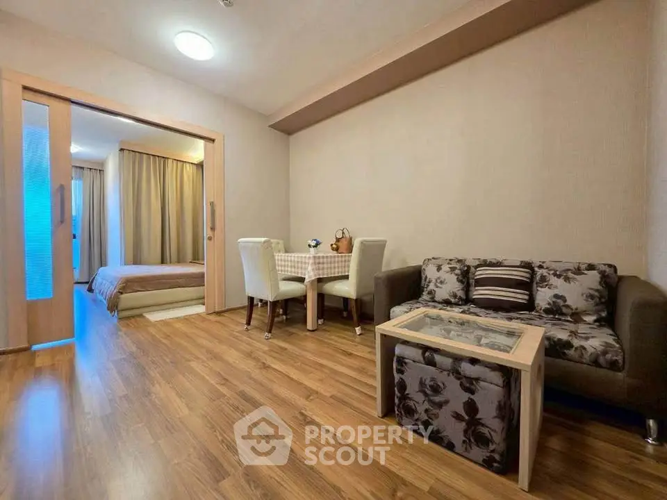 Modern living room with open layout and cozy dining area, featuring stylish furniture and warm wooden flooring.