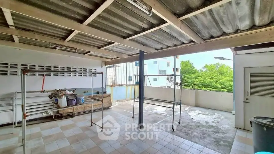 Spacious outdoor area with tiled flooring and partial roof, ideal for laundry or storage.