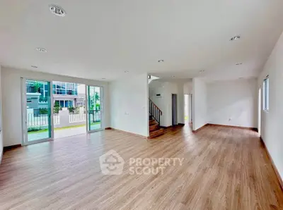 Spacious open-plan living room with wooden flooring and large windows in modern home.
