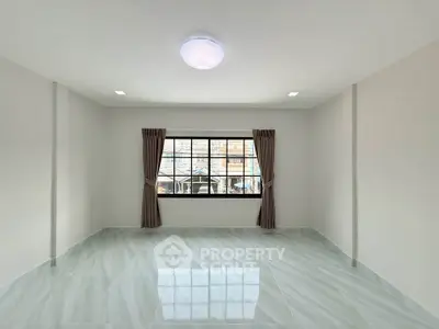 Spacious empty room with large window and tiled floor, perfect for customization.