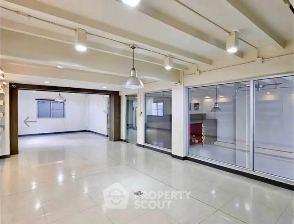 Spacious open-plan interior with modern lighting and large windows, ideal for versatile living or office space.