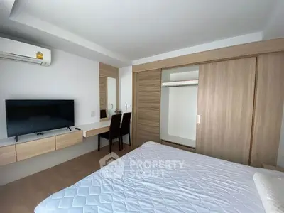 Modern bedroom with built-in wardrobe and wall-mounted TV in a stylish apartment.