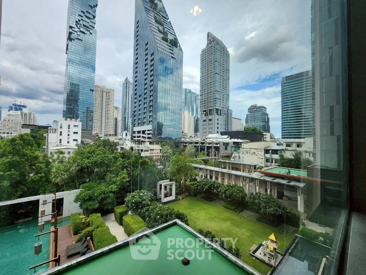 Stunning cityscape view from a high-rise building with lush garden and pool area.