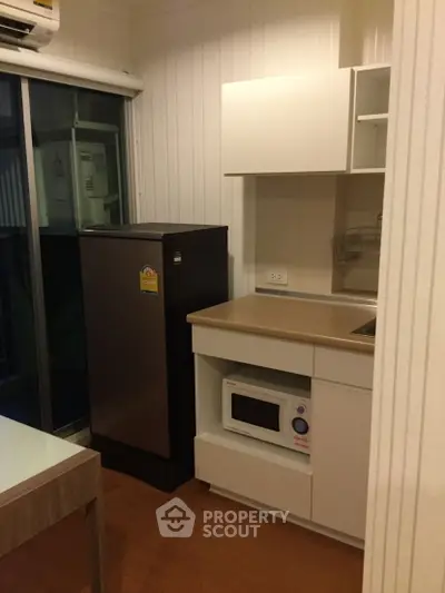 Compact kitchen with modern appliances and sleek cabinetry in cozy apartment.