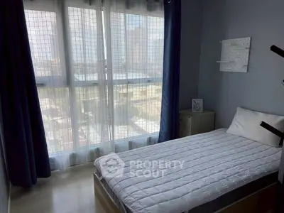 Cozy bedroom with large window offering city view, perfect for urban living.