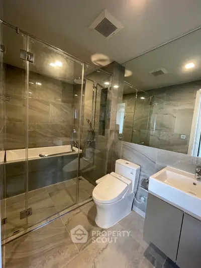 Modern bathroom with glass shower and sleek fixtures in luxury apartment.