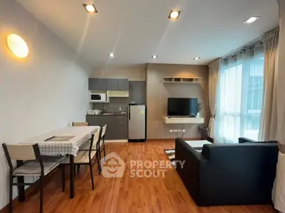 Modern living room with open kitchen, wooden flooring, and natural light