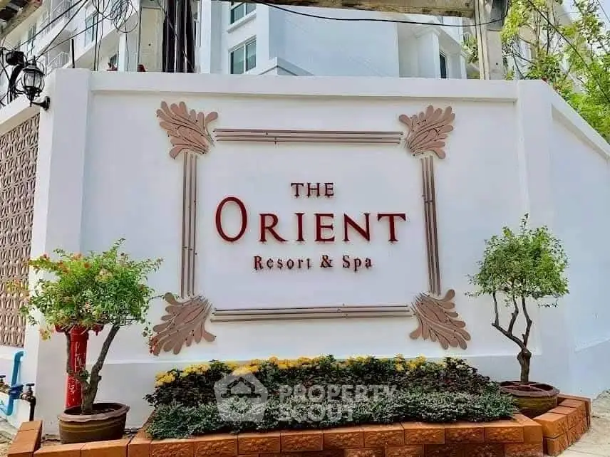 Elegant entrance sign of The Orient Resort & Spa with lush greenery.