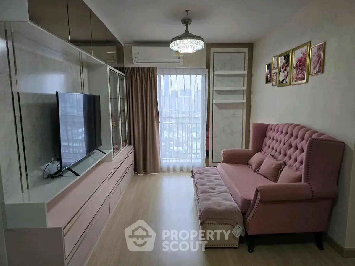 Chic living room with elegant pink sofa and modern entertainment unit, featuring a city view balcony.