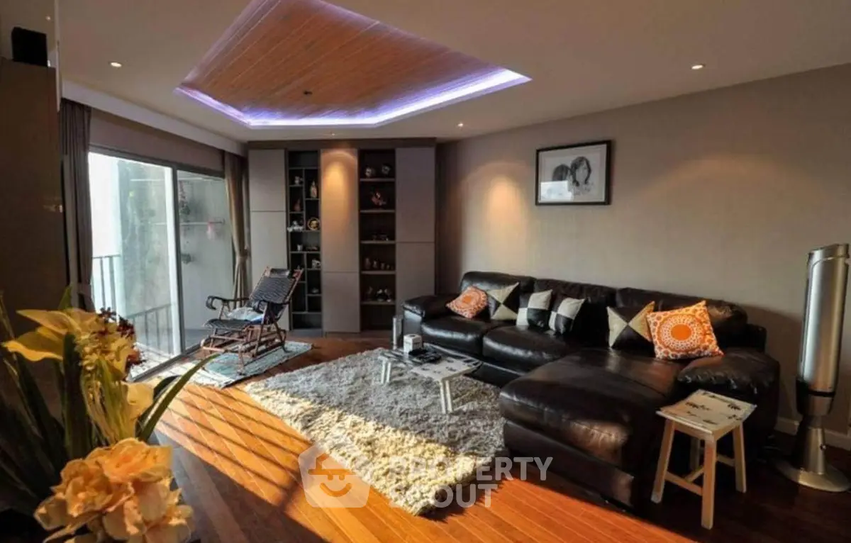 Luxurious living room with modern decor and natural light, featuring a cozy leather sofa and stylish shelving.