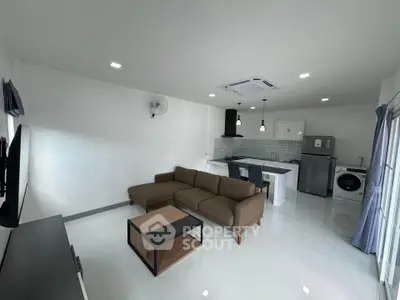 Modern open-plan living room with kitchen, featuring sleek furniture and appliances.