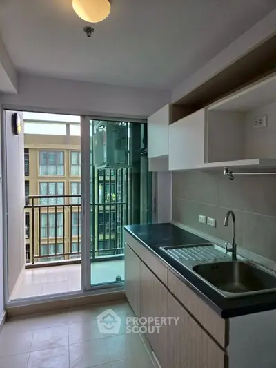 Modern kitchen with sleek cabinetry and balcony access in urban apartment