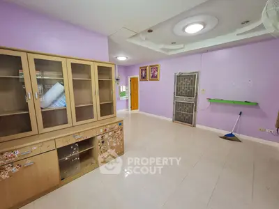 Spacious living room with large wooden cabinets and bright lilac walls, featuring modern lighting and pristine tiled flooring.