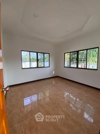 Spacious empty room with large windows and tiled flooring, perfect for customization.
