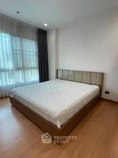 Spacious bedroom with large window and modern wooden flooring