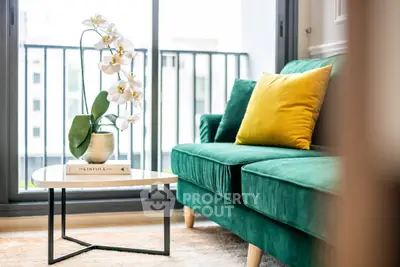 Stylish living room with green sofa, yellow pillow, and elegant orchid by the window.