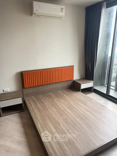 Modern bedroom with wooden bed frame, orange headboard, and balcony access.