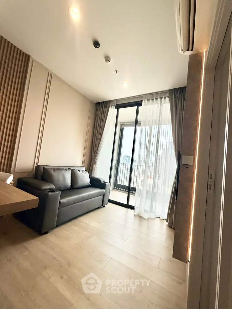 Modern living room with sleek sofa and city view balcony in high-rise apartment.