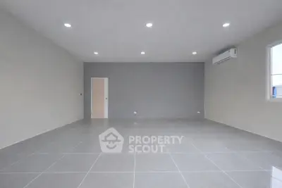 Spacious empty room with modern tiled flooring and air conditioning, ready for customization.