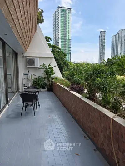 Spacious balcony with lush greenery and city skyline view, perfect for relaxation and outdoor dining.